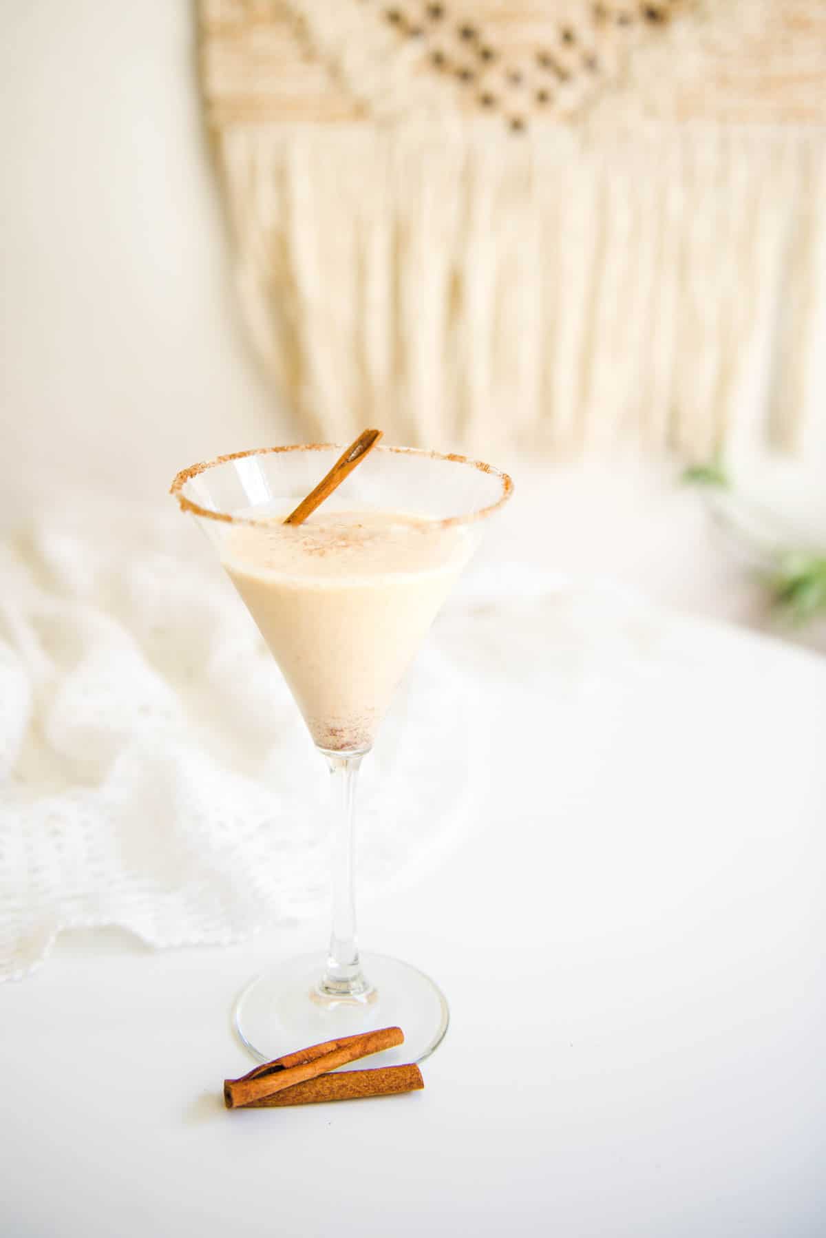 A pumpkin martini in a cinnamon rimmed martini glass on a table.