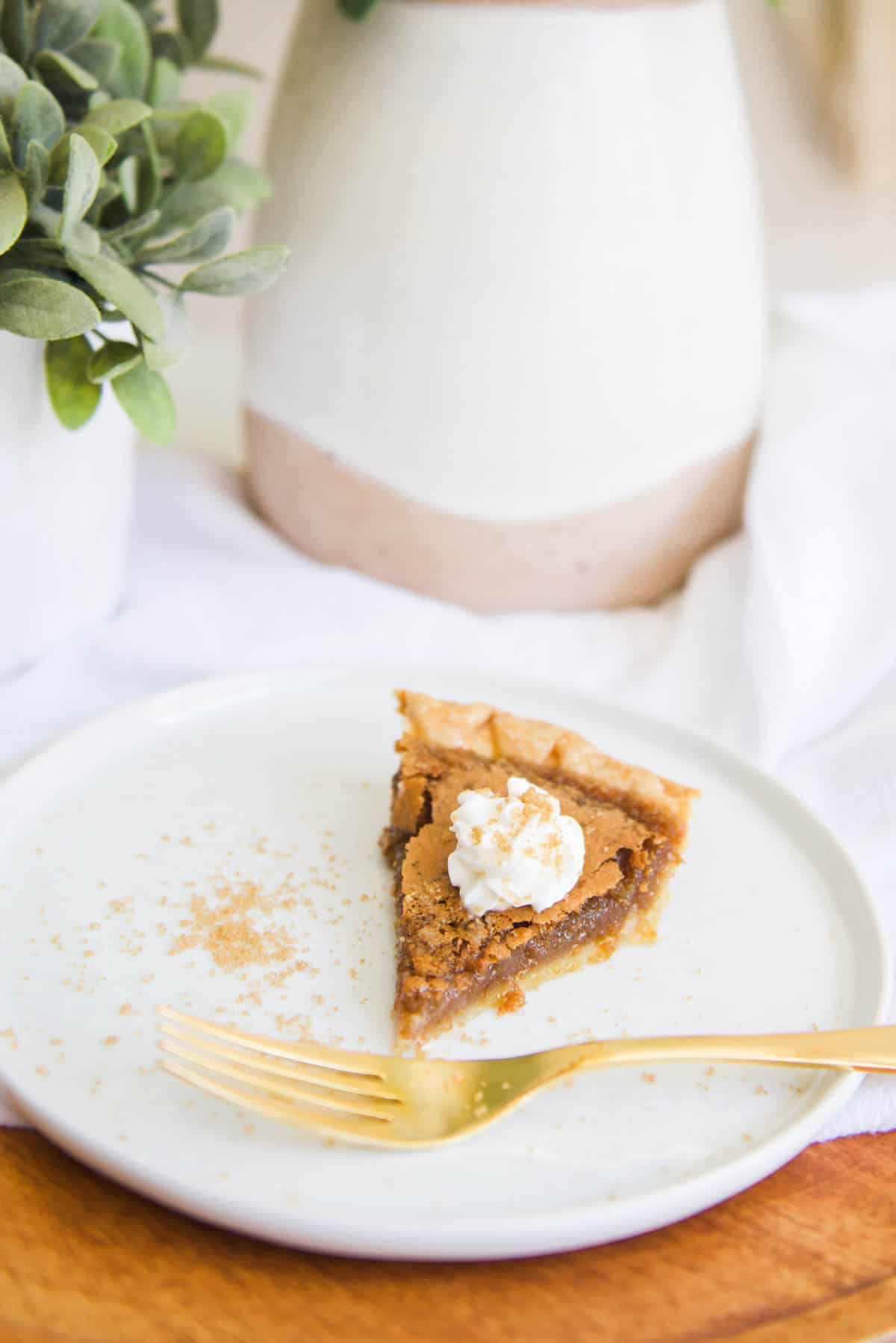 A slice of Brown Sugar Pie on a plate topped with whipped cream.