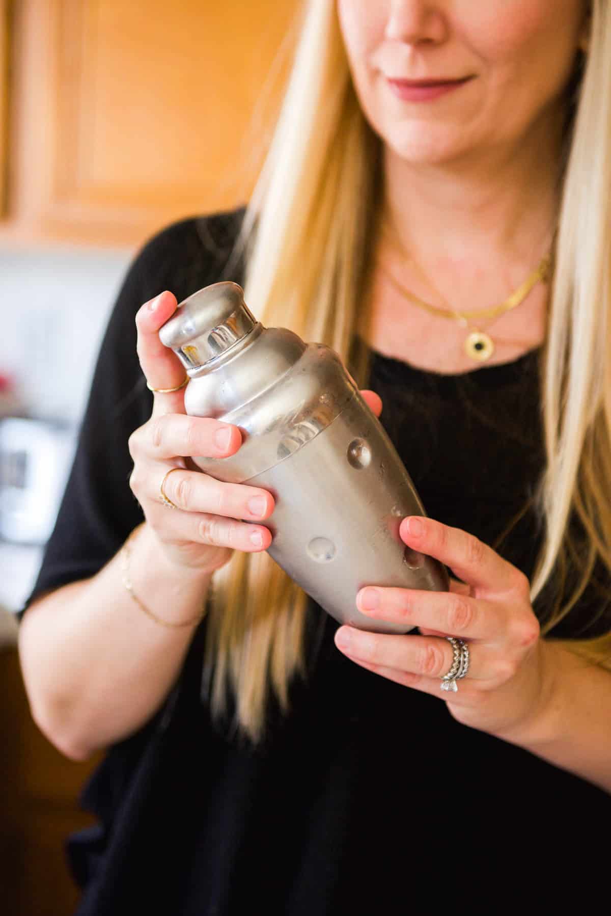 Woman shaking a cocktail in a cocktail shaker.