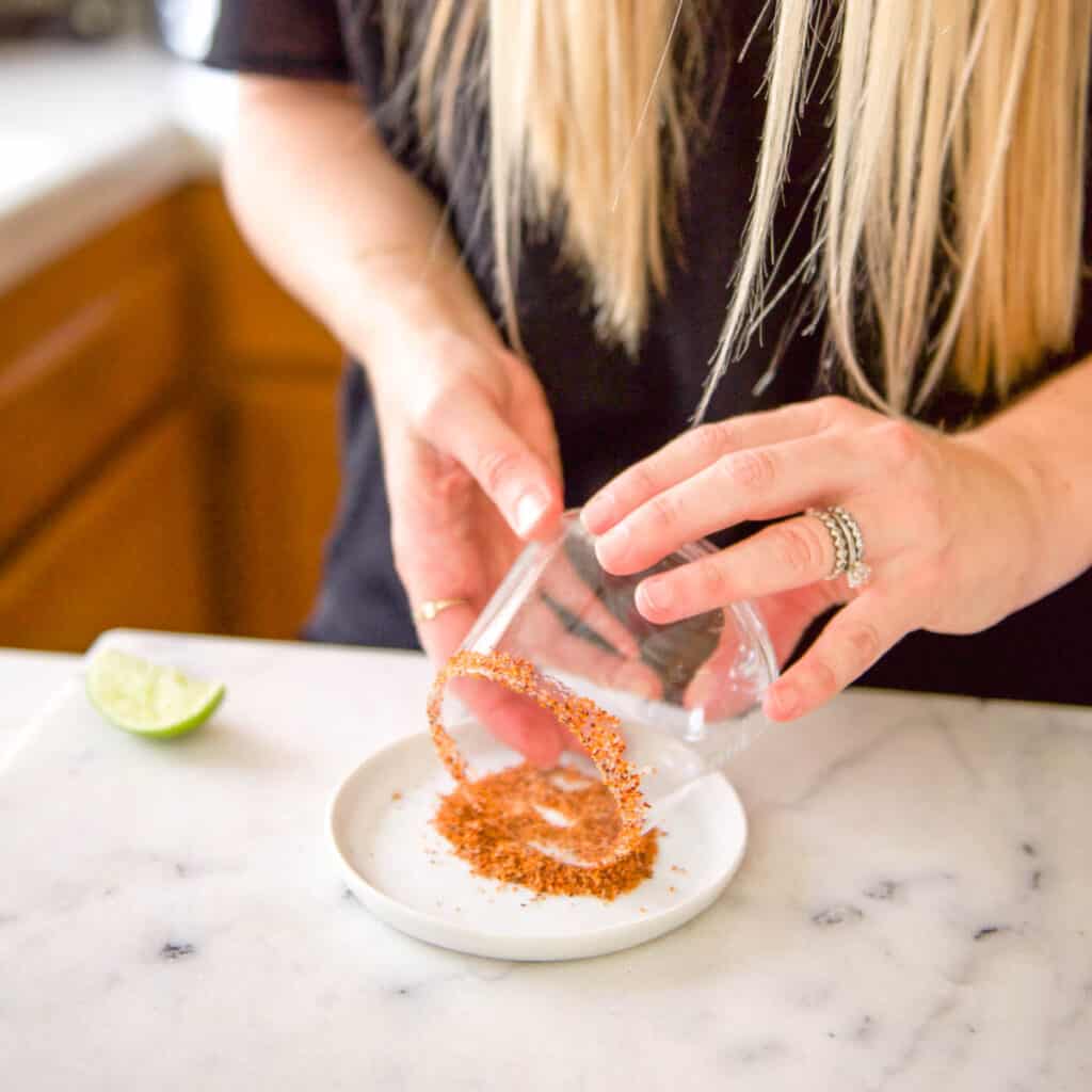 Rolling a rim of a cocktail glass in Tajin.