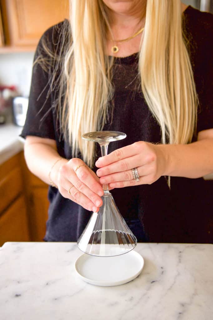 Dipping a martini glass in a plate of water to rim it with sugar.