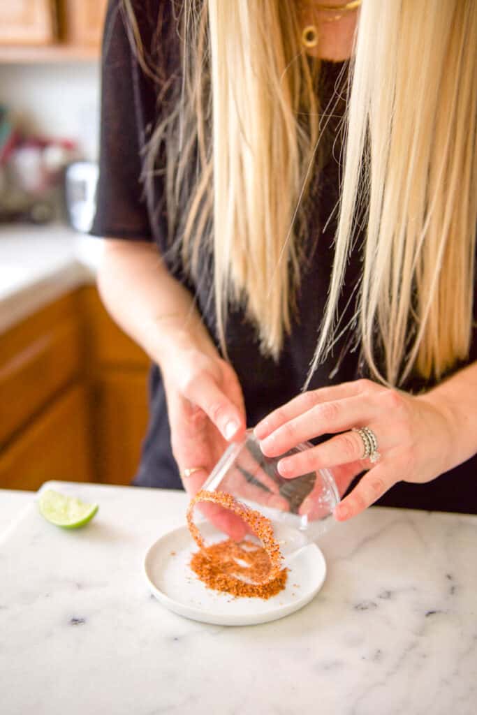 Rolling the cocktail glass in tajin.