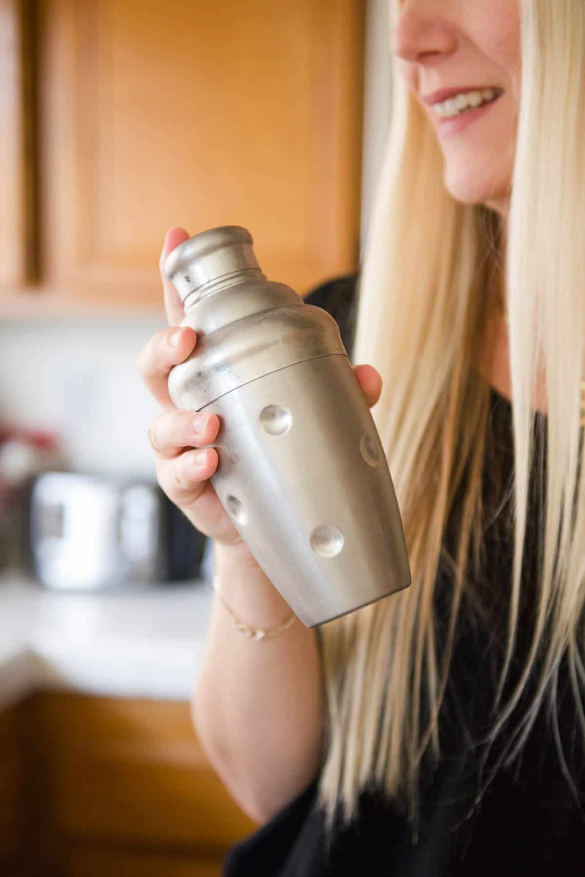 Woman shaking a cocktail shaker.