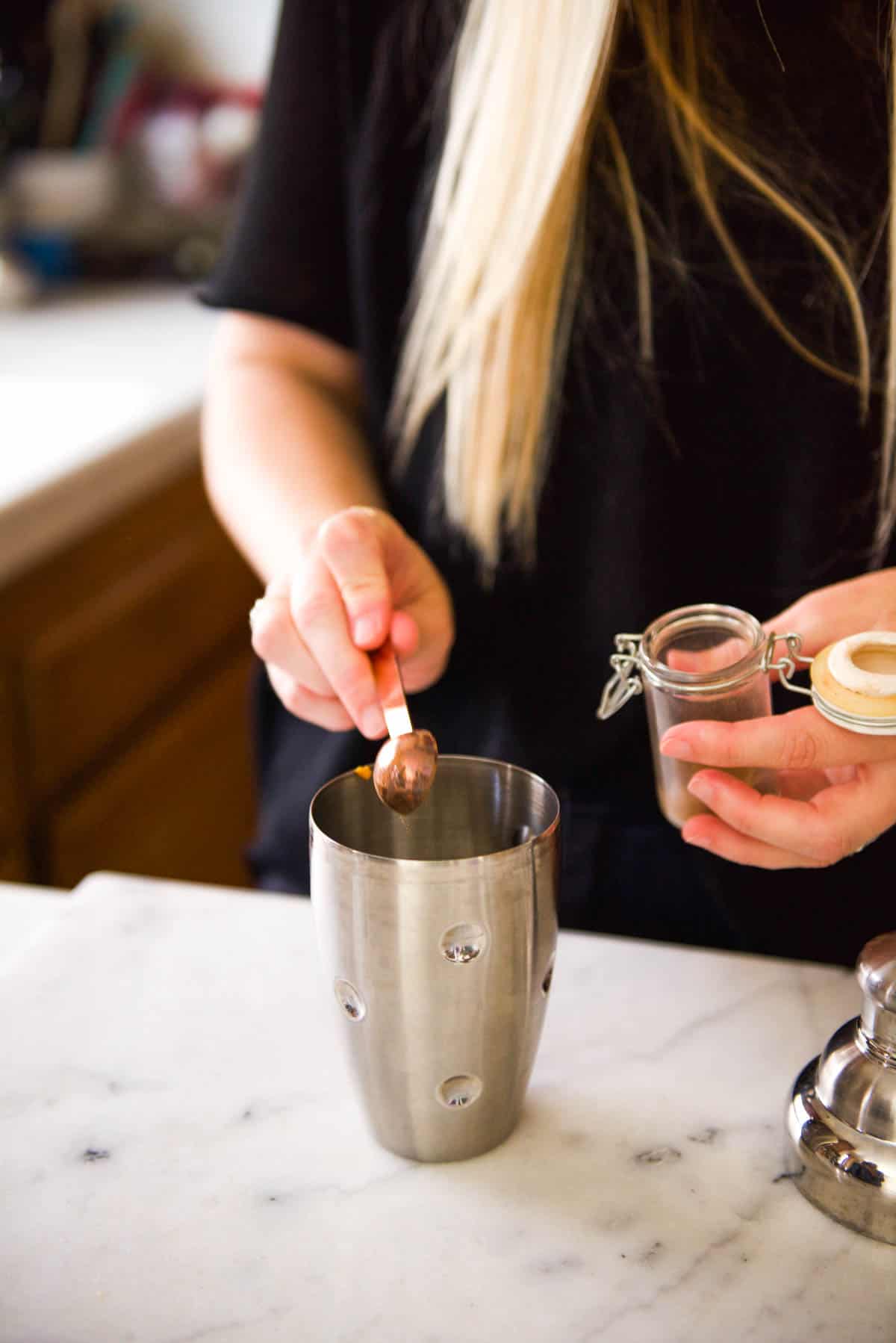 Adding pumpkin pie spice to a cocktail shaker for a pumpkin martini.