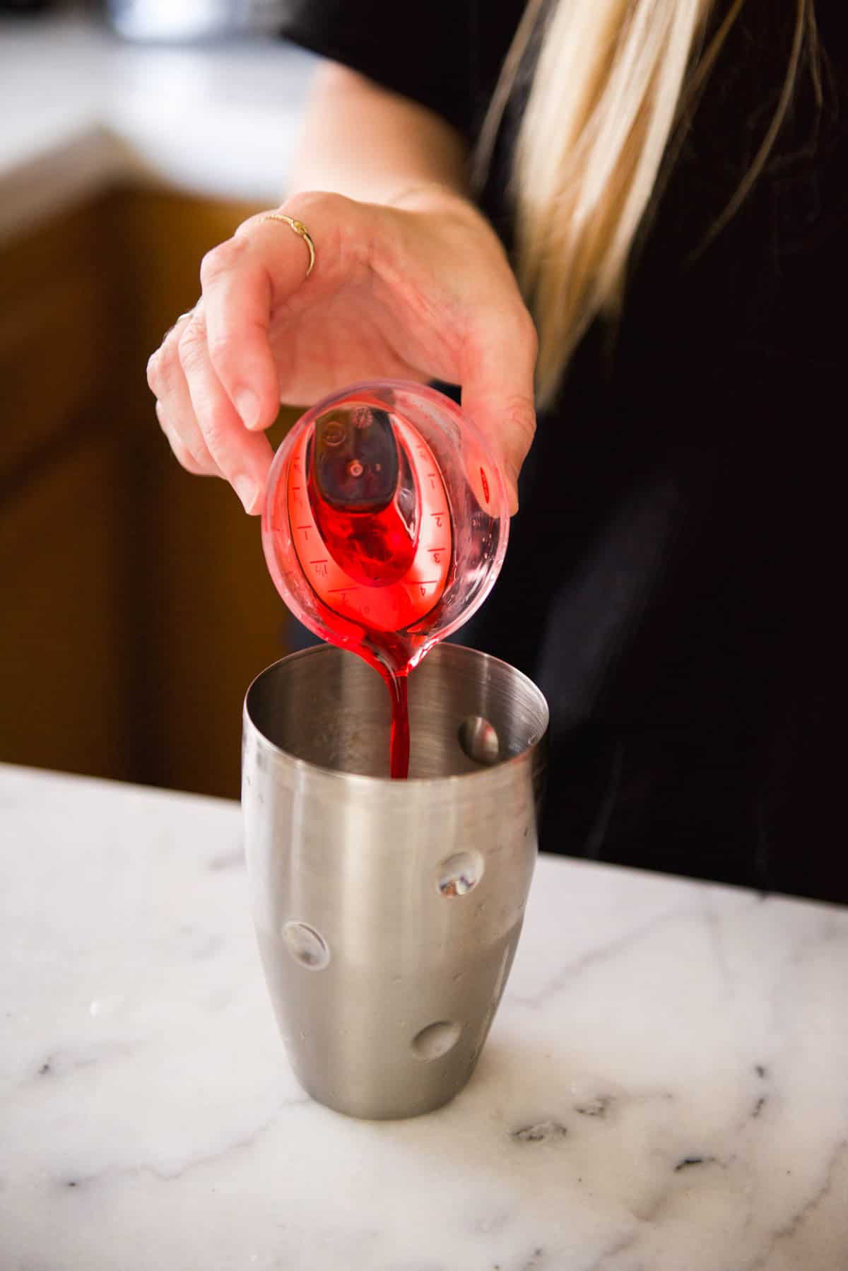 Adding grenadine to a cocktail shaker.