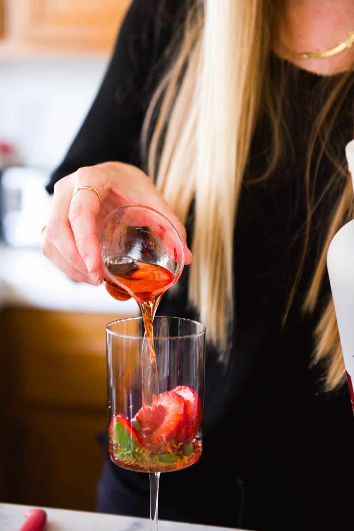 Adding a red liquor to a wine glass for a cocktail.