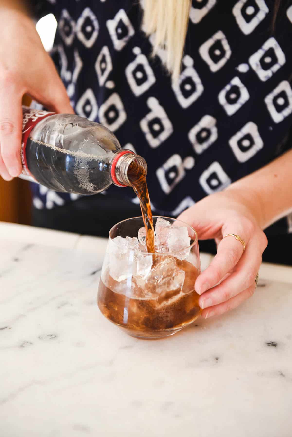 Woman pouring Dr. Pepper into a cocktail glass.