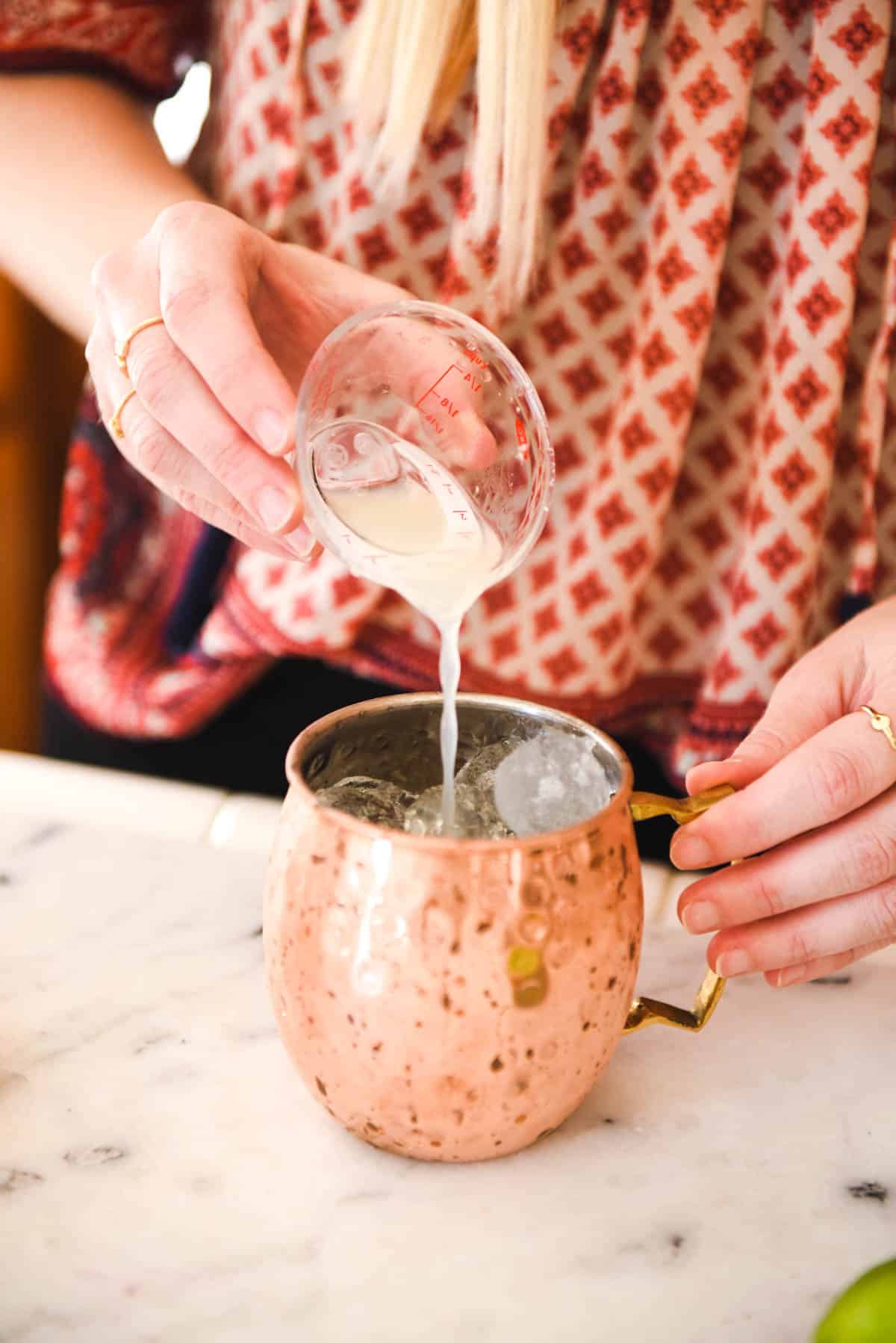 Adding fresh lime juice to a cocktail in a copper mug.