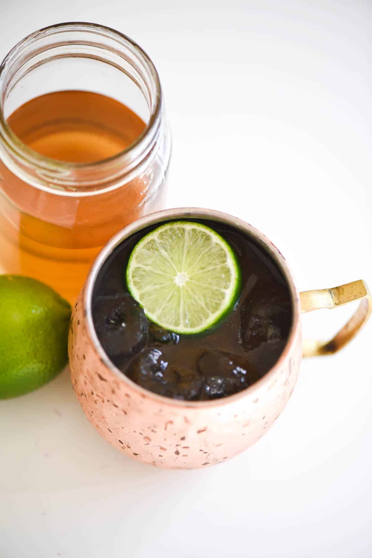 A jar of vanilla simple syrup next to a copper moscow mule mug.