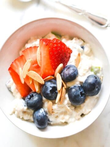 Close up of Corner Bakery Overnight Oatmeal in a bowl with fresh strawberries, blueberries and almonds.