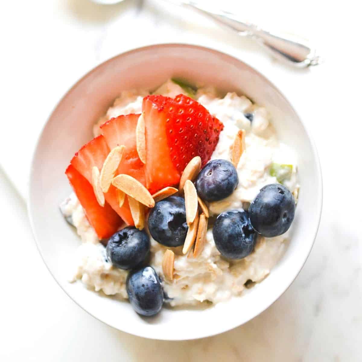 Close up of Corner Bakery Overnight Oatmeal in a bowl with fresh strawberries, blueberries and almonds.