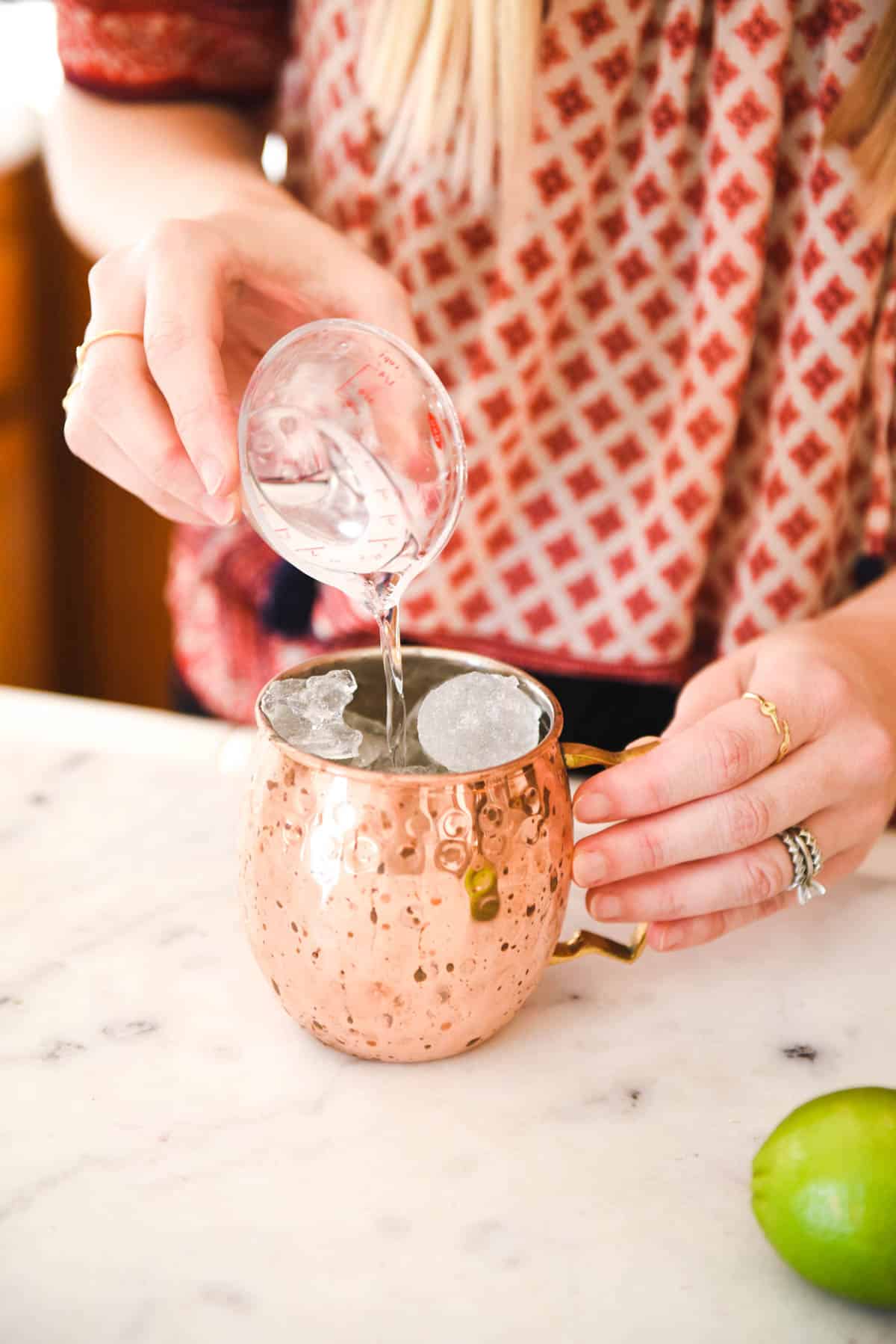 Adding vodka to a copper moscow mule mug.