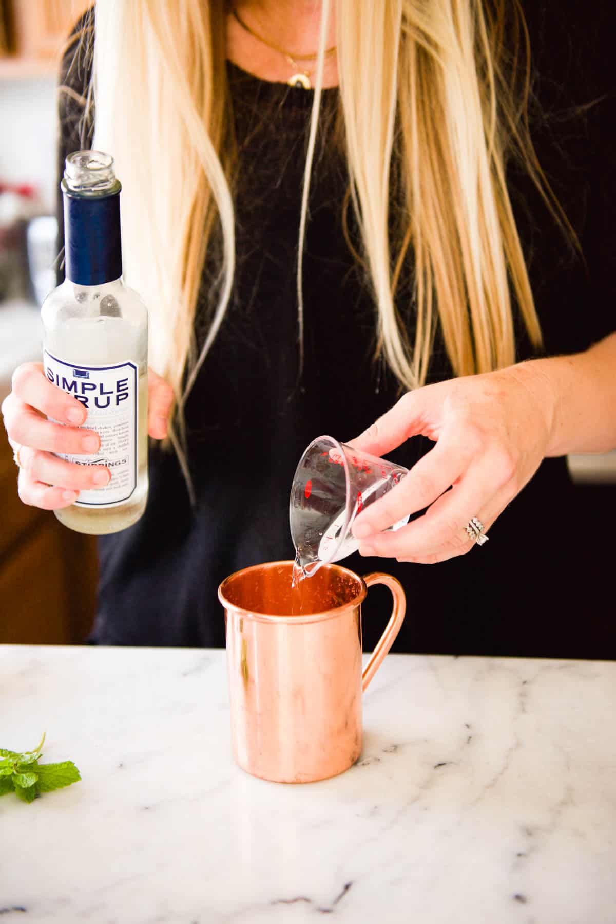 Pouring simple syrup into a copper cocktail mug.