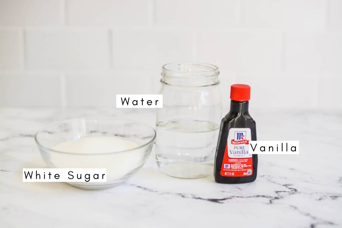 Labeled ingredients to make homemade Vanilla Simple Syrup with vanilla extract on a table.