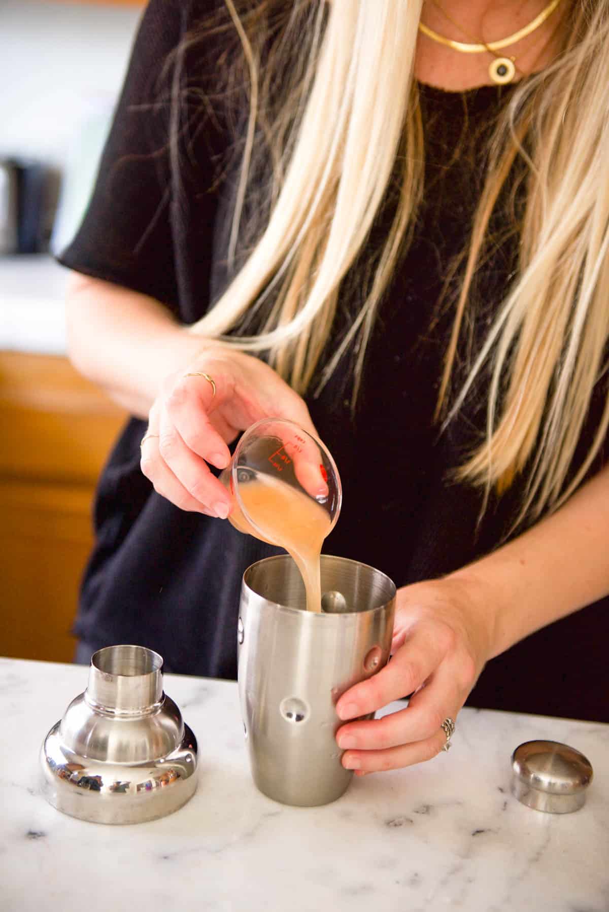 Adding fresh grapefruit juice to a cocktail shaker.