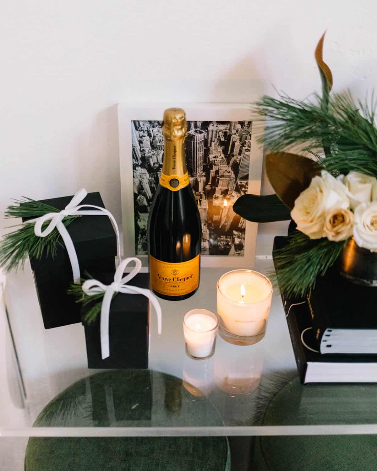 An entry table with holiday gifts, candles and a bottle of champagne.