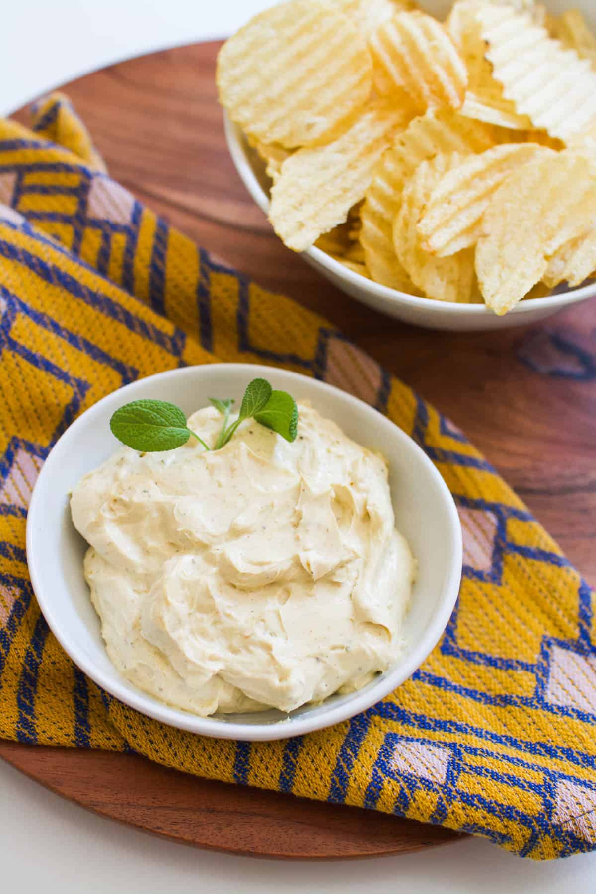 Overhead shot of a small bowl of dip next to a bowl of potato chips.