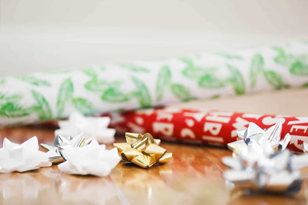 Close up of stick on bows and holiday wrapping paper on the ground. 