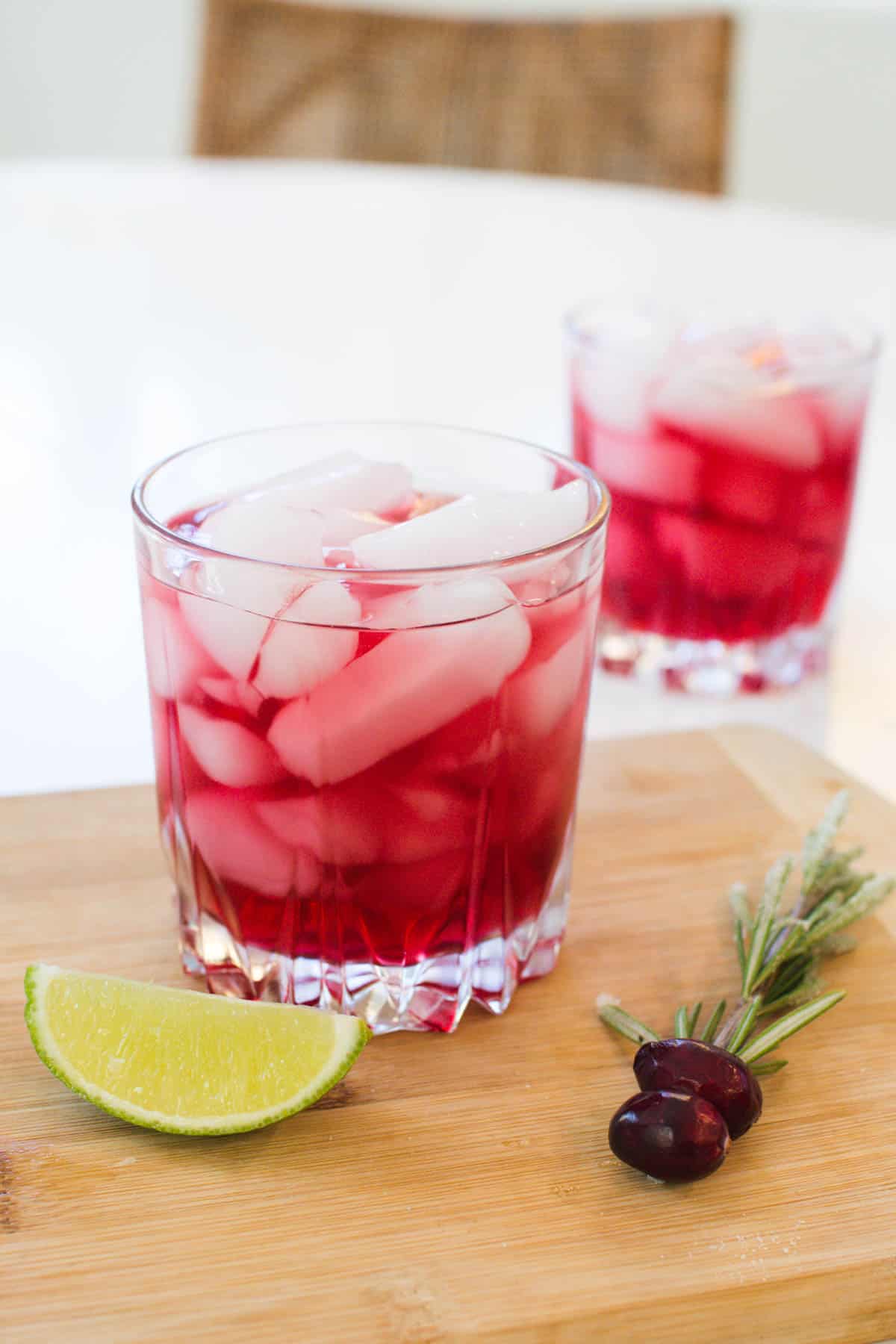 A cocktail glass with cranberry juice and vodka on a tray next to a piece of lime.