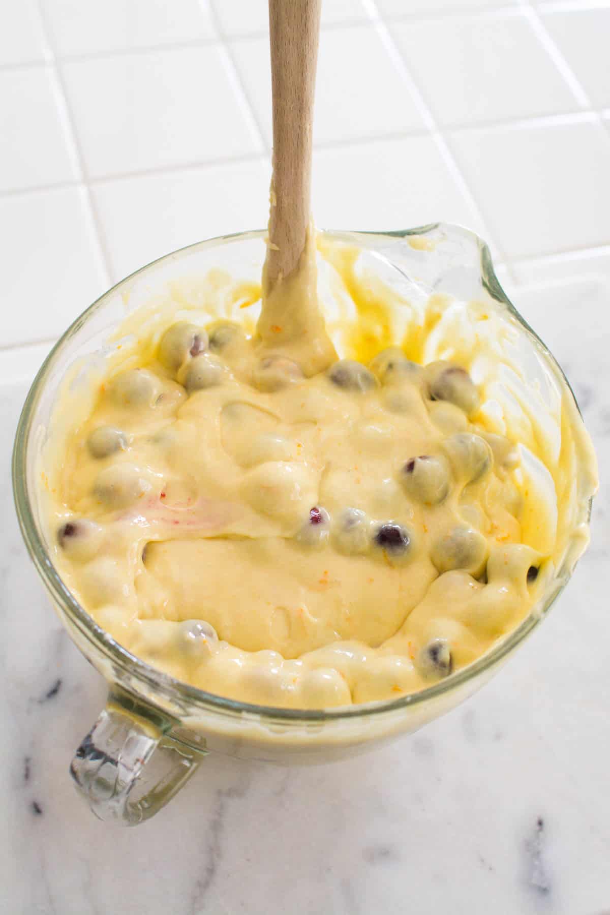 Boxed cake mix batter in a glass bowl with fresh cranberries mixed in.