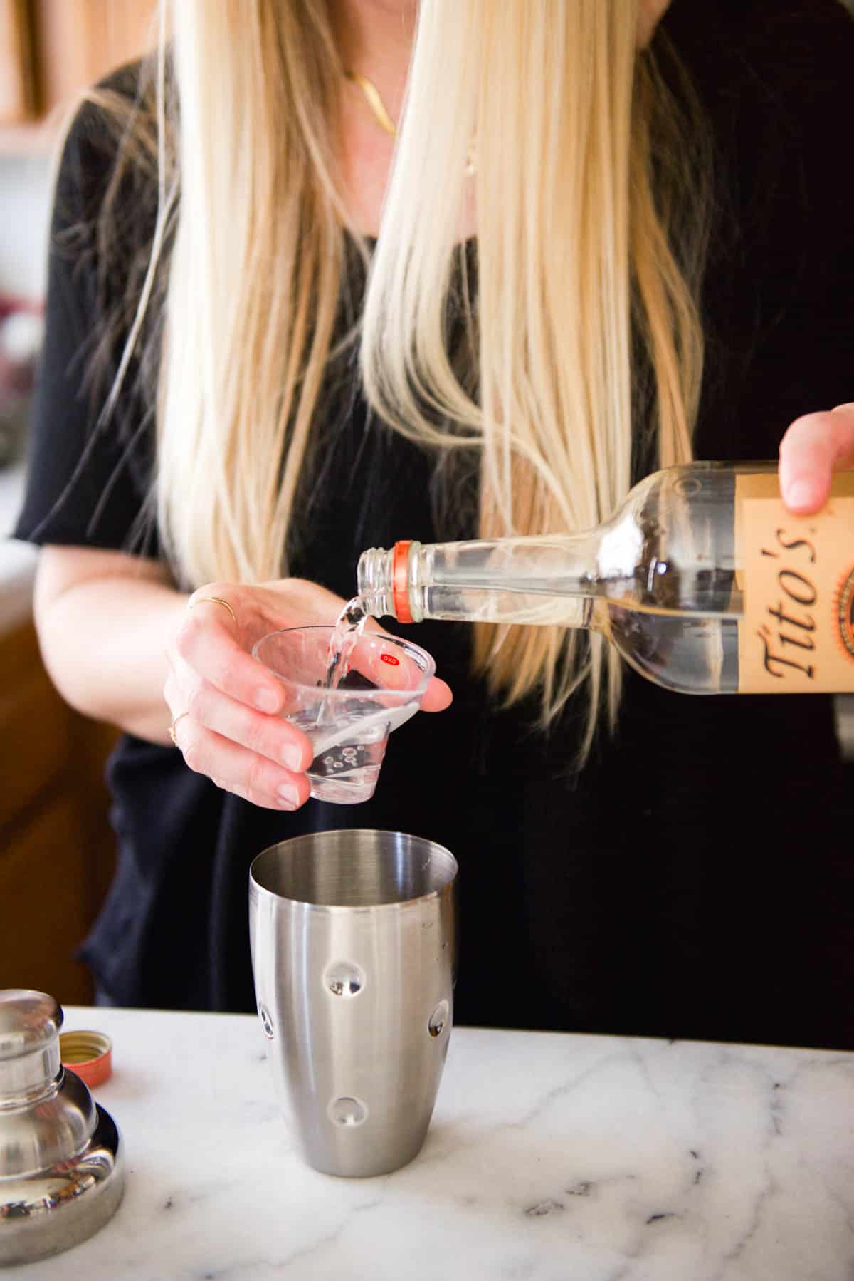 Woman measuing out vodka for Moscow Mules.