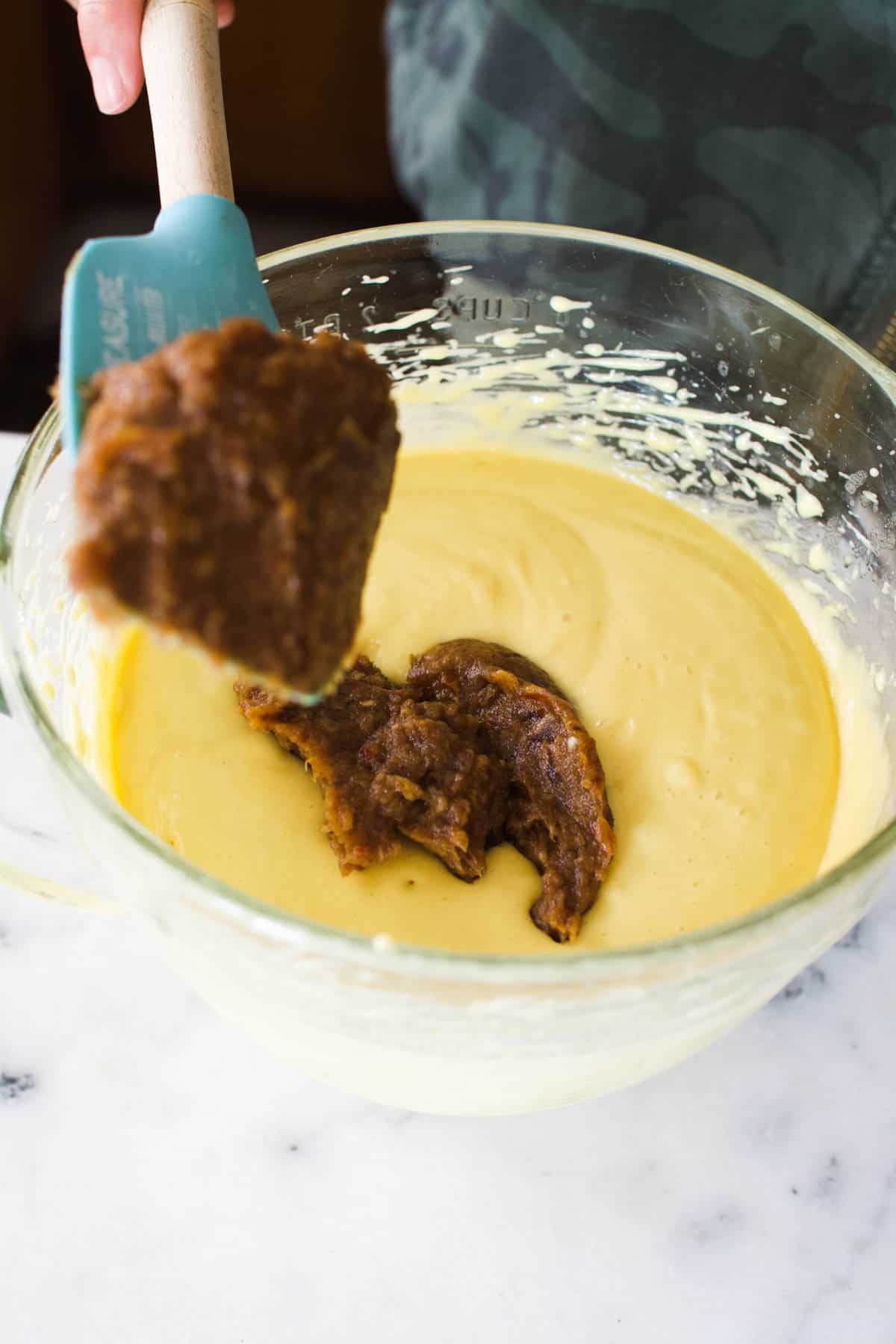 Woman mixing in a date paste to cake batter.