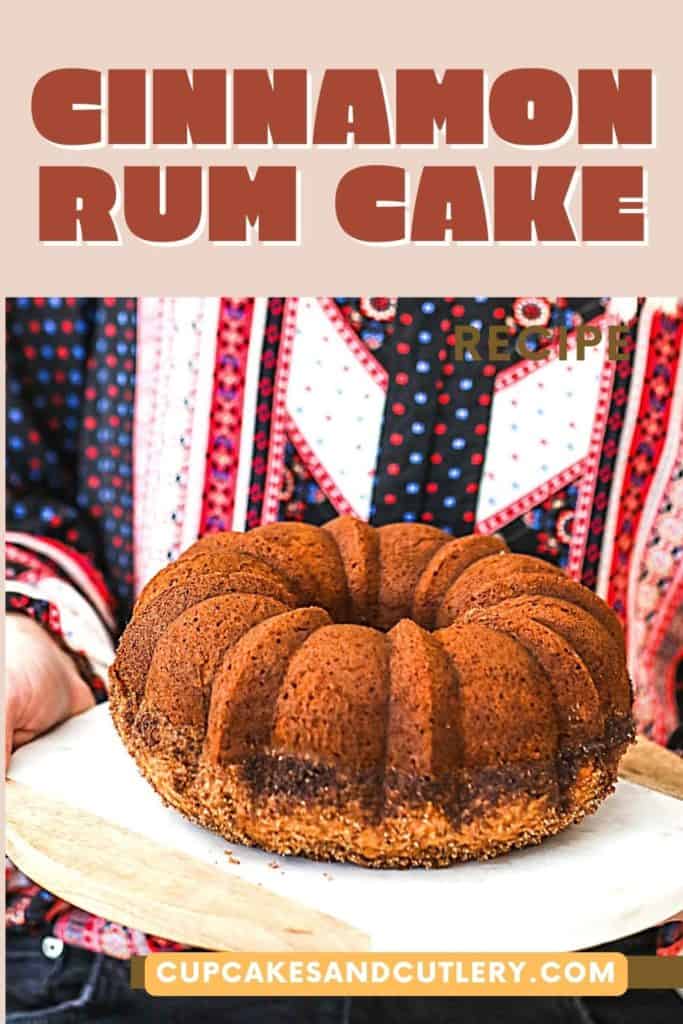 Woman holding a cinnamon rum bundt cake on a marble cake board.