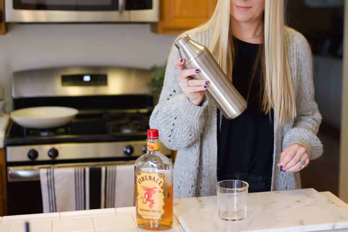 A woman shaking up a cocktail in a cocktail shaker.
