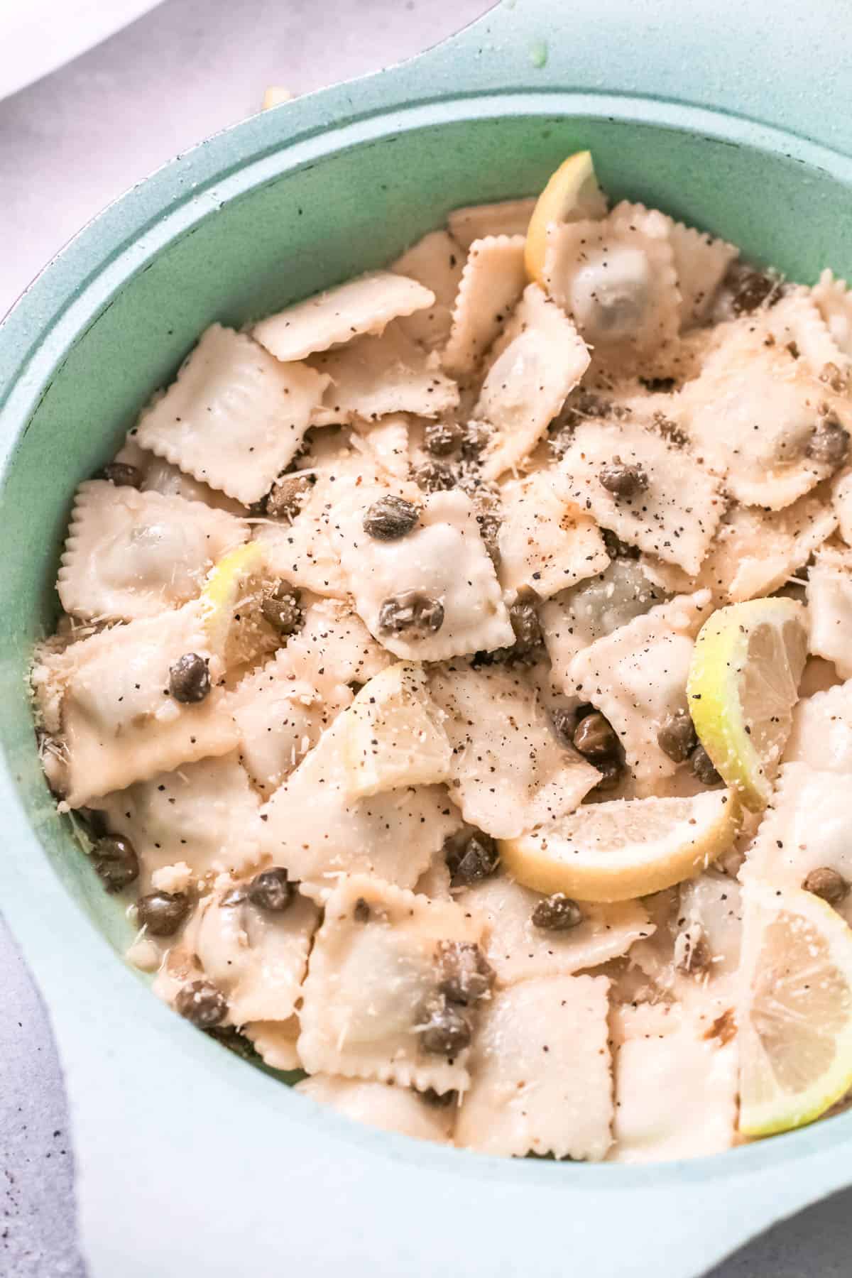 Close up of capers and lemon slices mixed with ravioli.