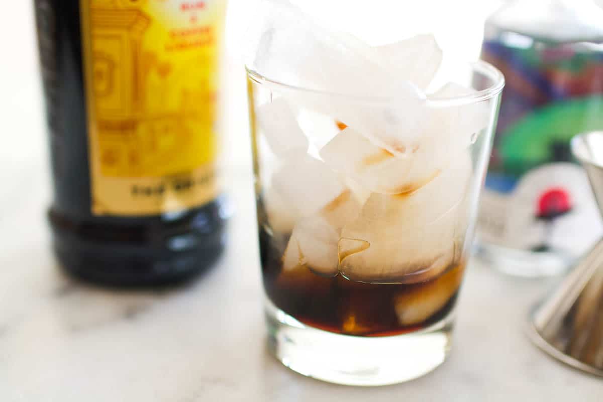 A glass with Kahlua and ice for a Black Russian drink.