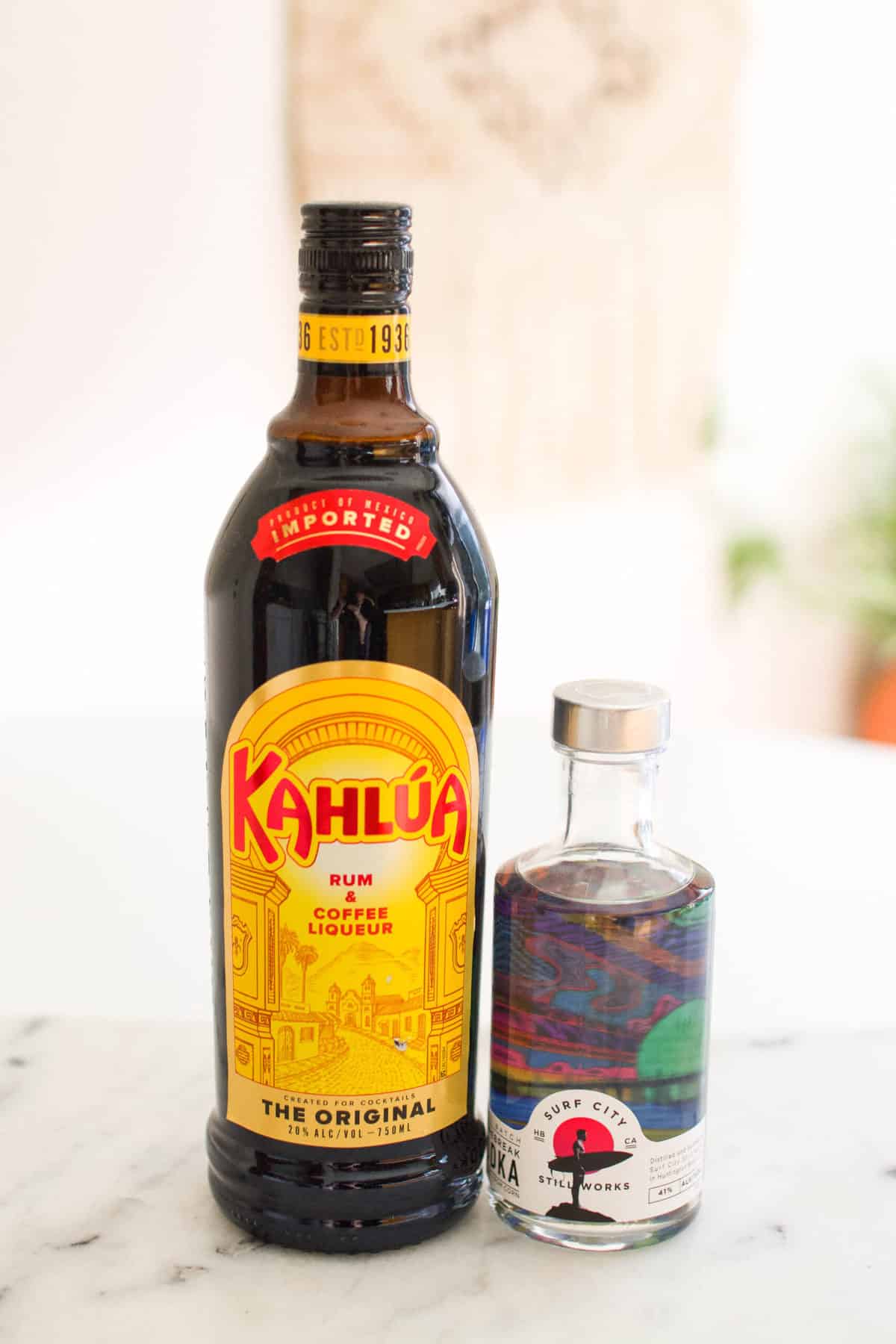 A bottle of Kahlua and vodka on a counter to make a Black Russian cocktail.