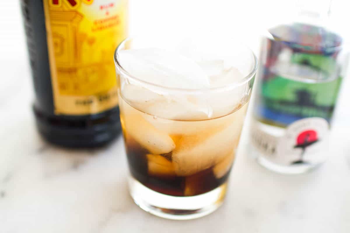 A glass with ice and Kahlua and vodka on a counter.