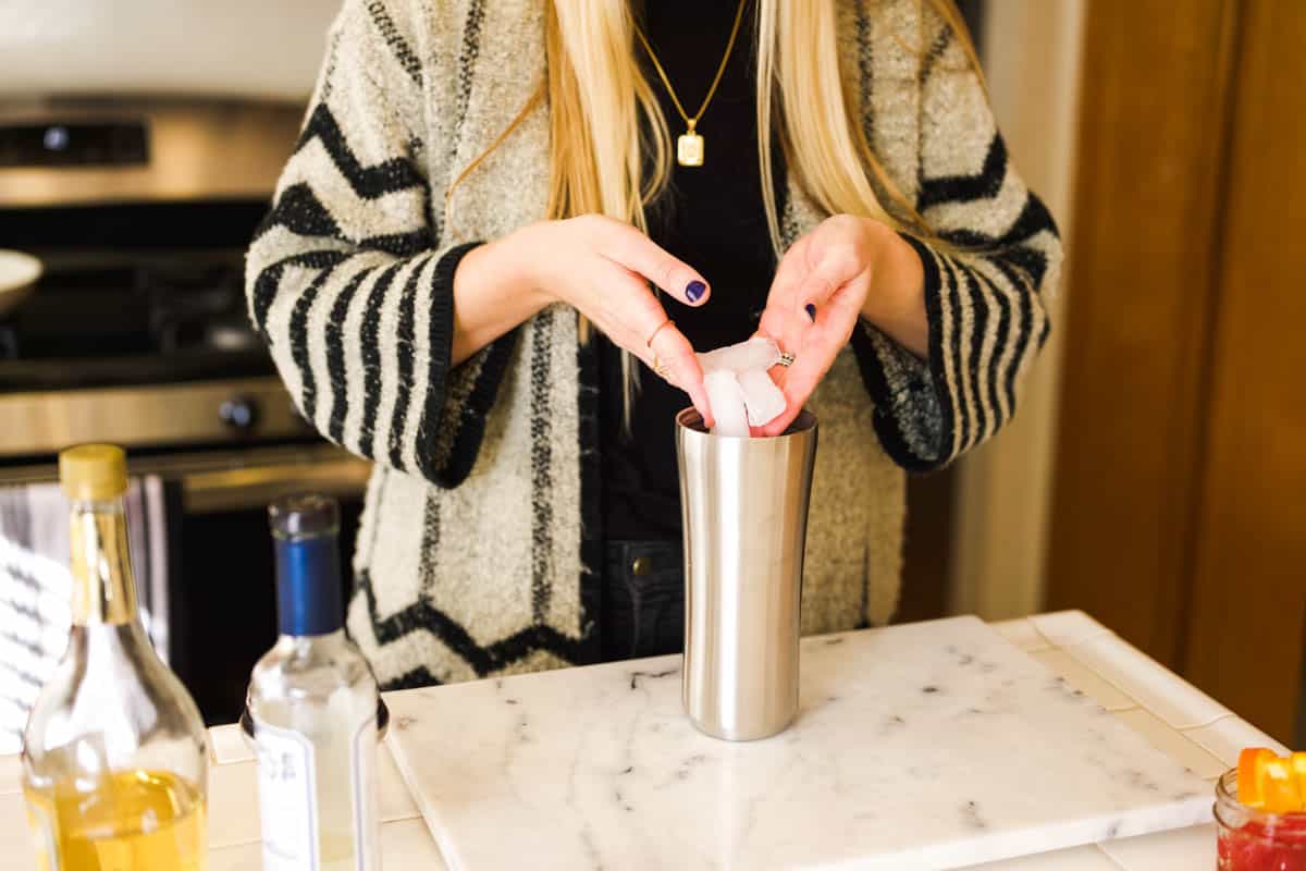 Woman adding ice to a cocktail shaker.