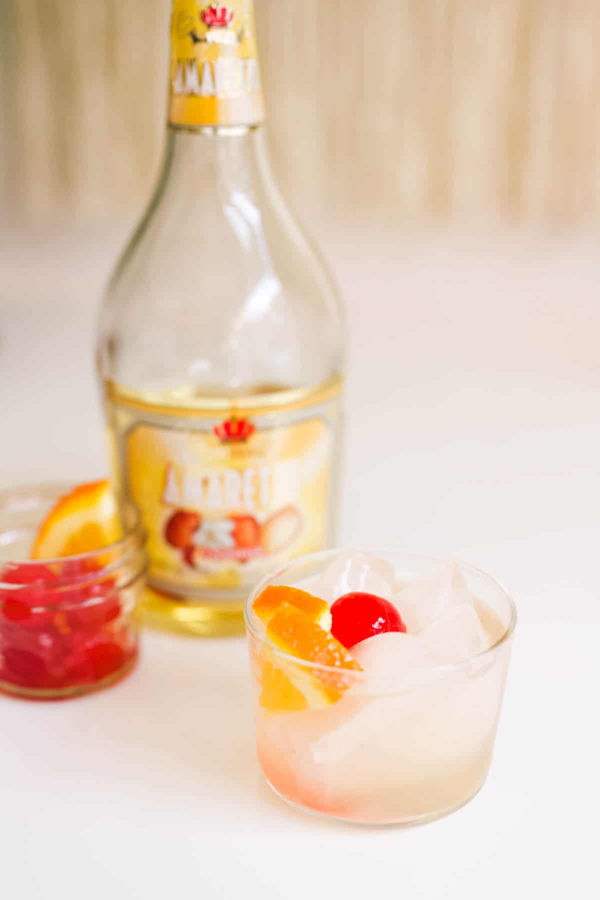 An Amaretto Sour drink on a table next to a bottle of Amaretto.