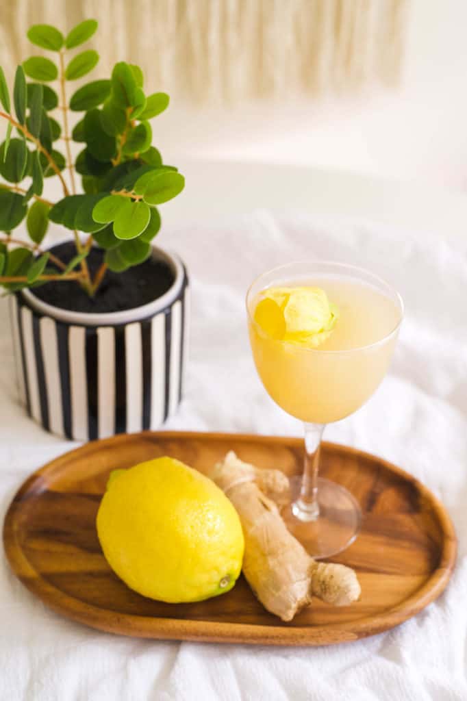 A lemon tequila cocktail in a Nick and Nora cocktail glass on a small wooden tray on a table.