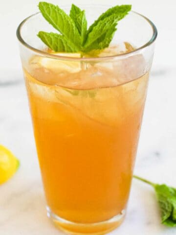 Tall glass of iced tea with vodka garnished with mint.