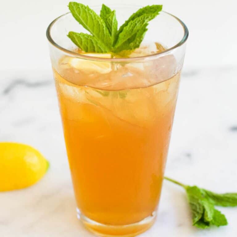 Tall glass of iced tea with vodka garnished with mint.