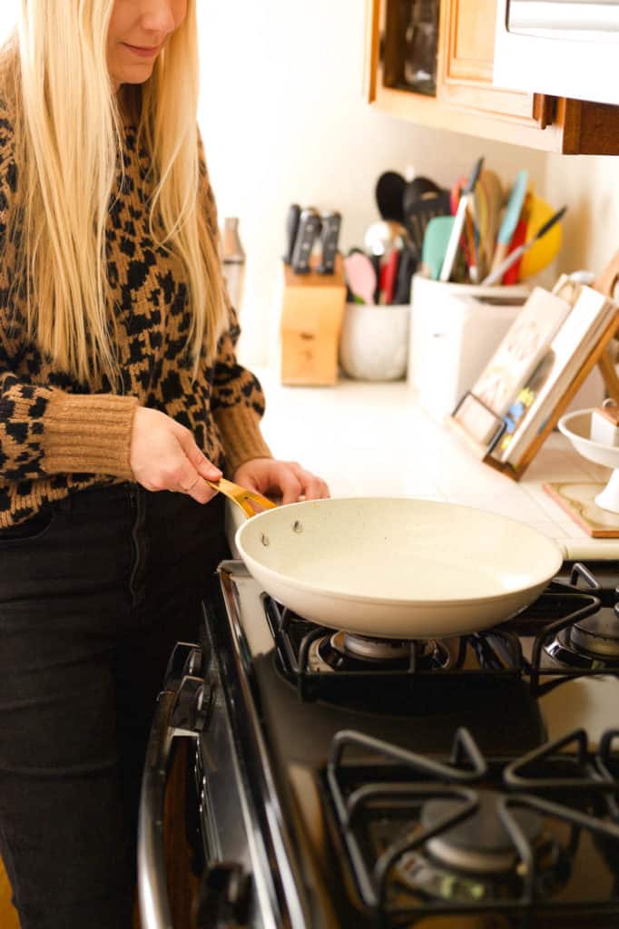 Woman setting down a pan on the stove.