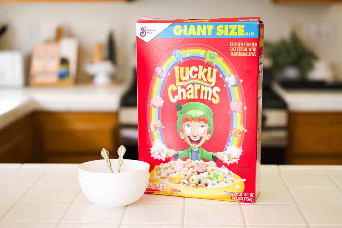 Box of Lucky Charms on the counter next to bowls.