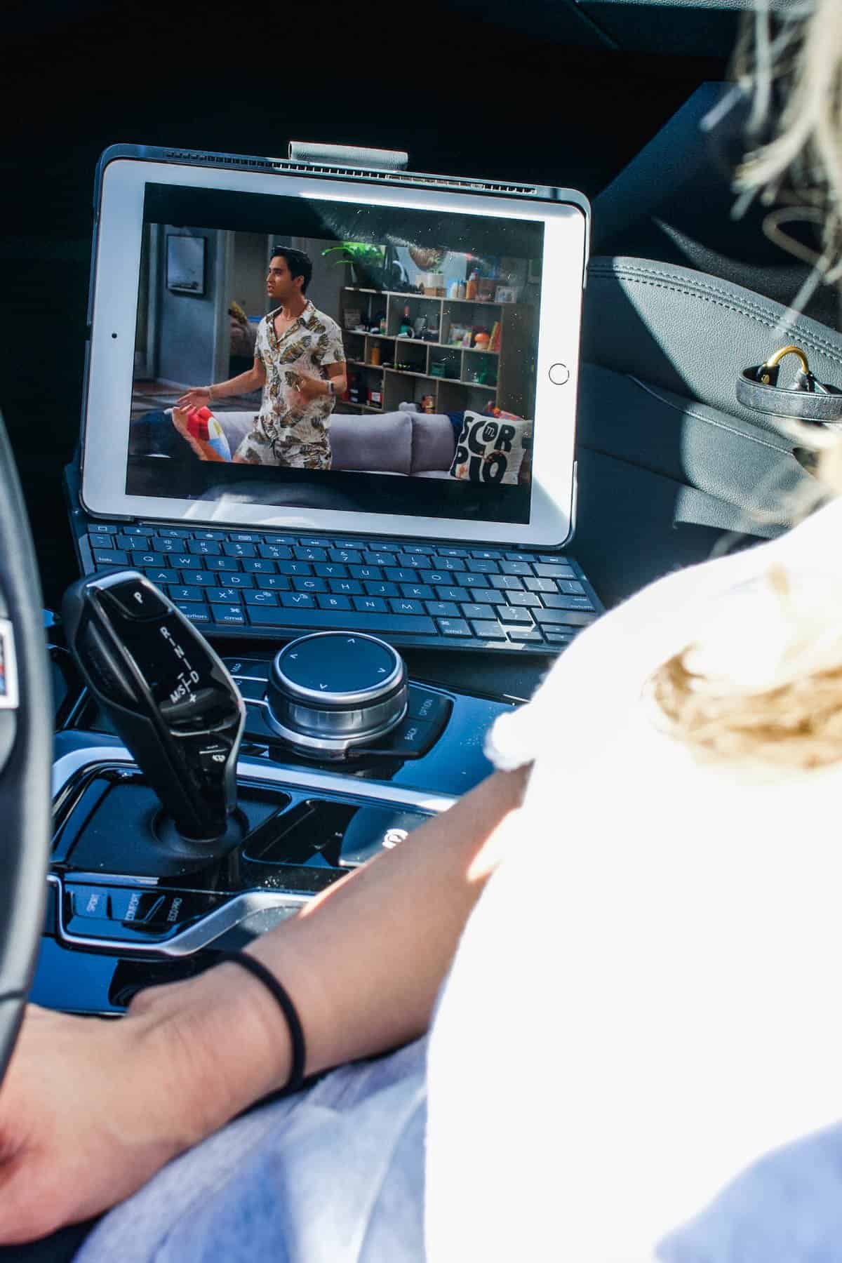 A mom waiting in the car watching an Ipad.