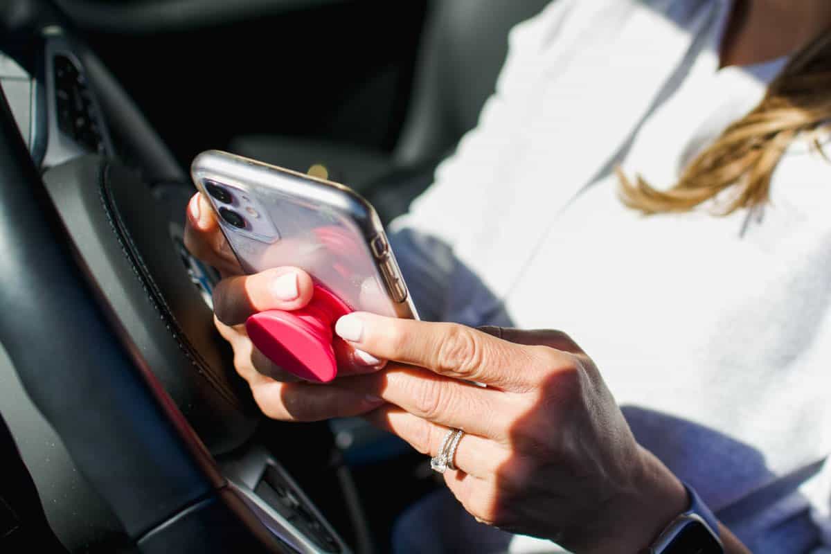 Woman holding her cell phone in the car.