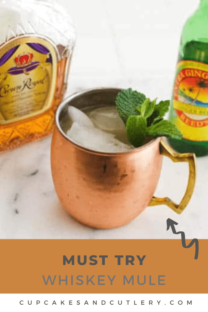Text - Must Try Whiskey Mule over an image with a copper mug holding a Moscow Mule cocktail made with whiskey next to a bottle of ginger beer and a bottle of Crown Royal.