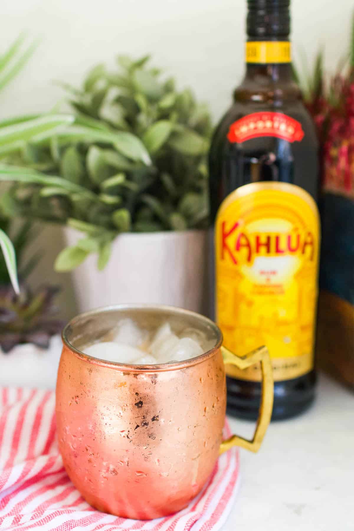 Kahlua Mule in a copper mug on a table next to a bottle of coffee flavored liqueur.