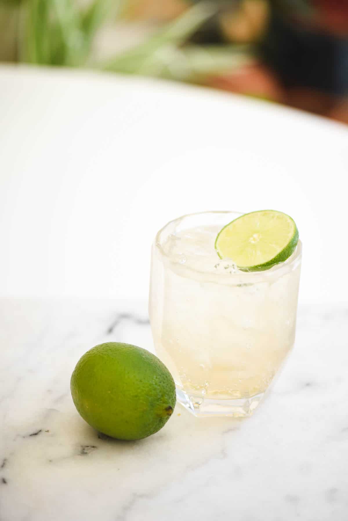 A short cocktail glass on a table with ginger ale and tequila.