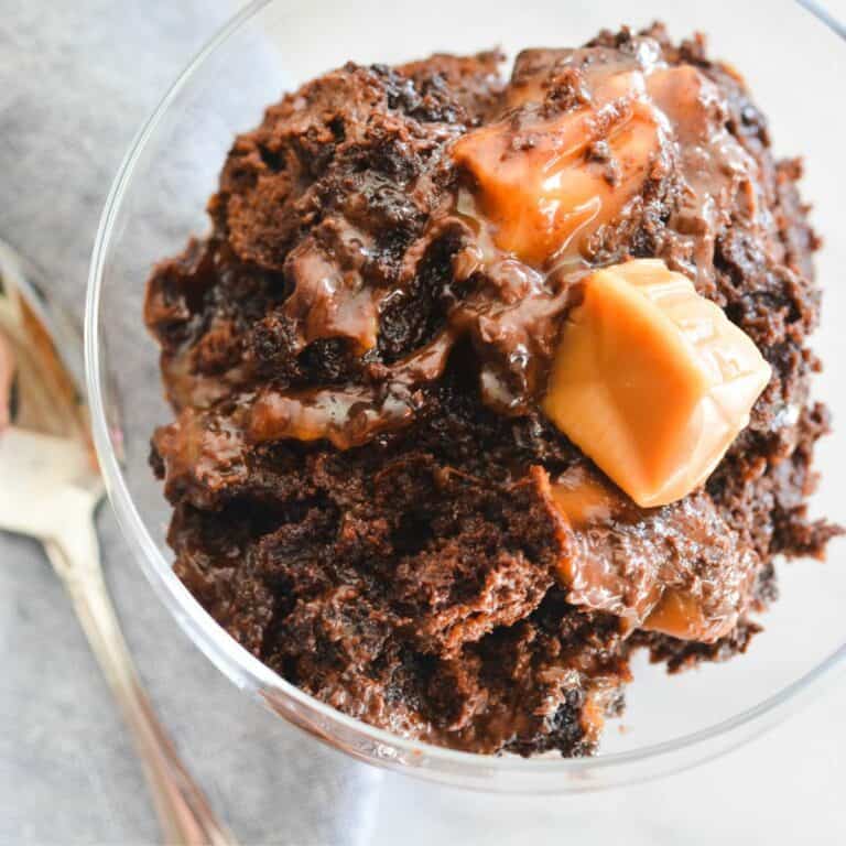 Close up of a dump cake made with chocolate cake mix and caramel candies in a glass dessert bowl.