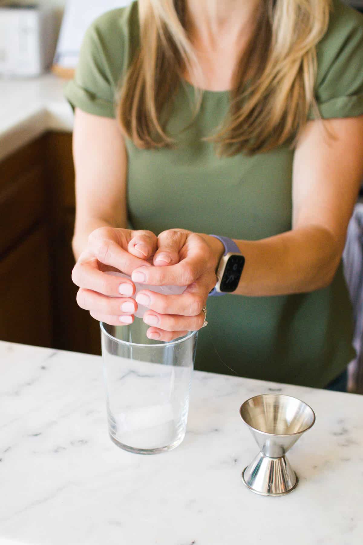 Woman adding ice to a cocktail glass.