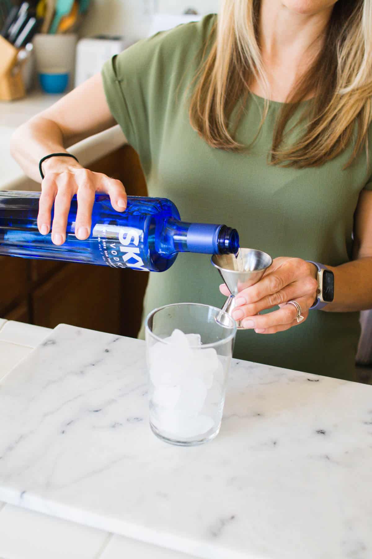 Woman adding vodka to a glass with ice.