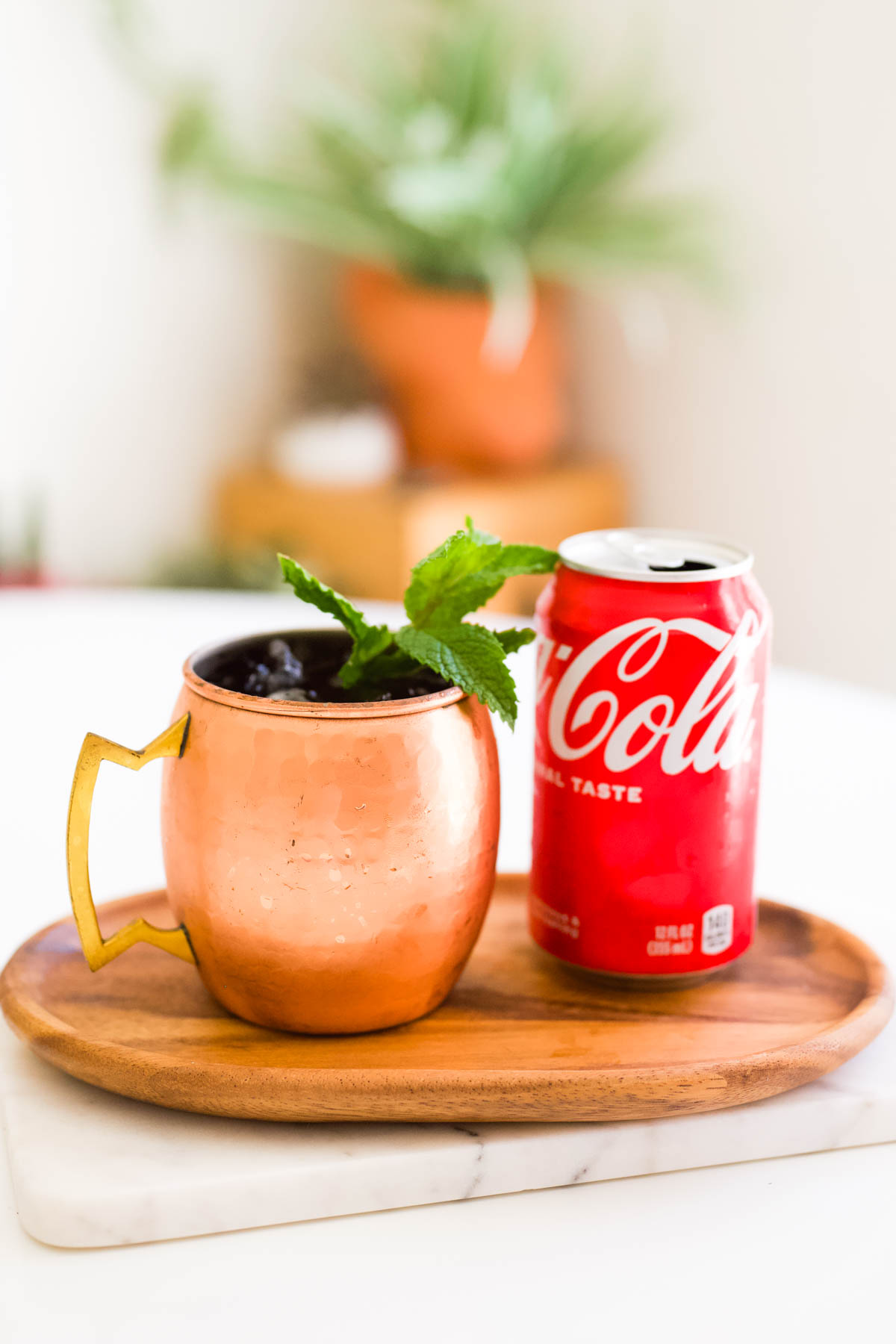 A wooden tray with a copper mug and a can of Coke.