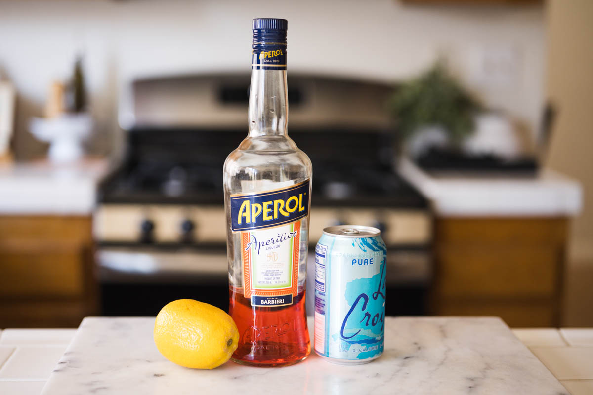 Ingredients to make an Aperol Soda on a counter.