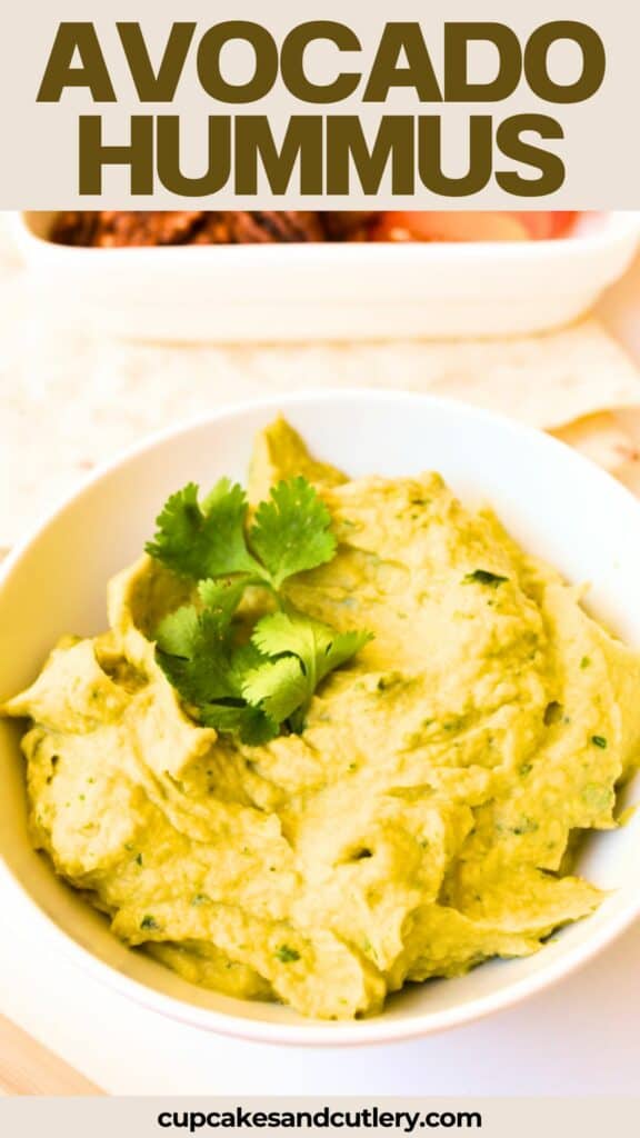 Close up of a white bowl of green hummus topped with cilantro.